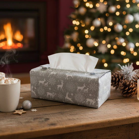 Tissue box cover with white reindeer and snowflakes on a grey background displayed in a living room and dining room