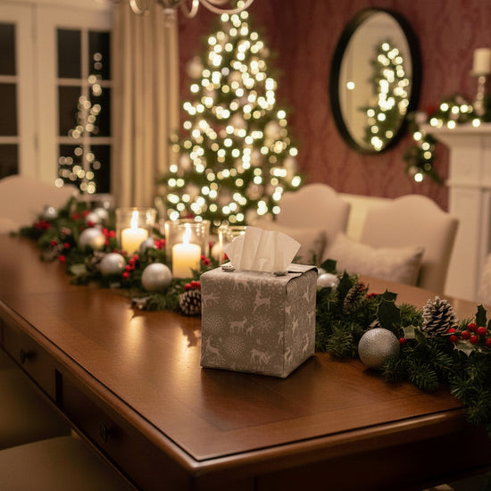 Tissue box cover with white reindeer and snowflakes on a grey background displayed in a living room and dining room